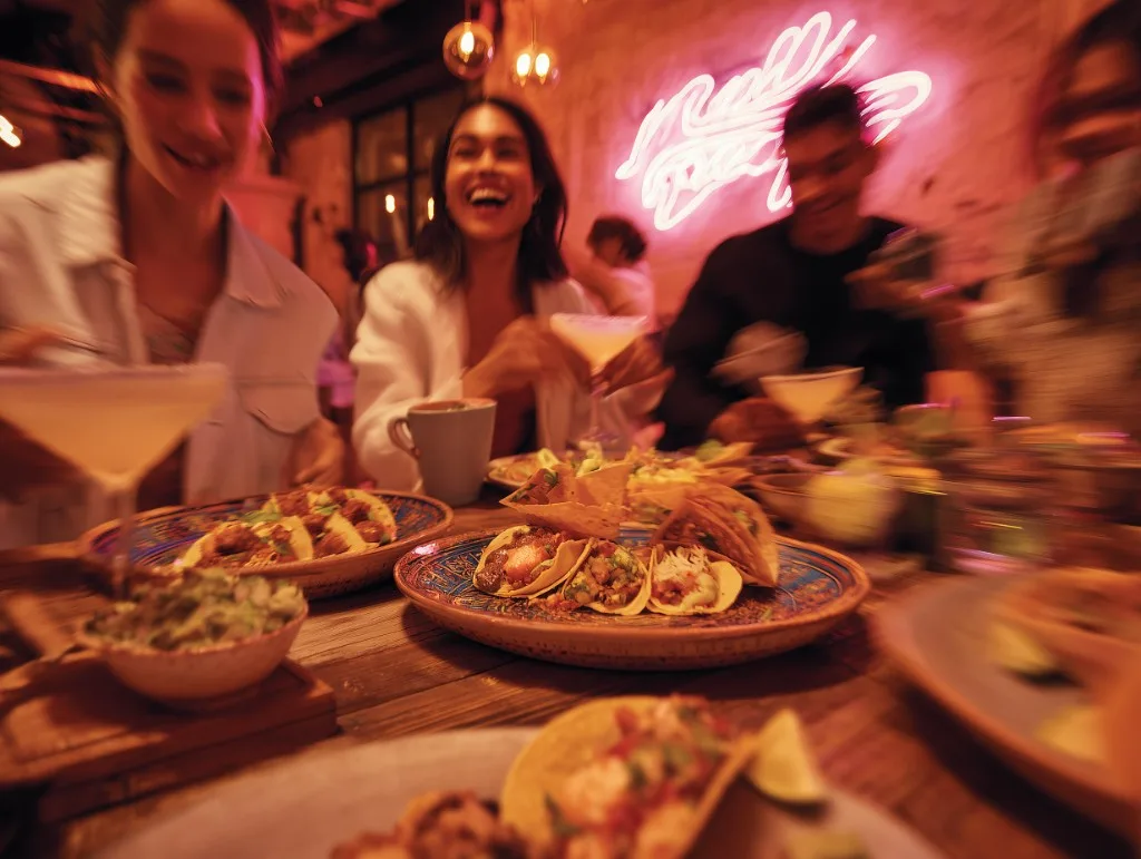 Friends sharing tacos, guacamole and margaritas at a lively group dinner at Superchido, Seddon